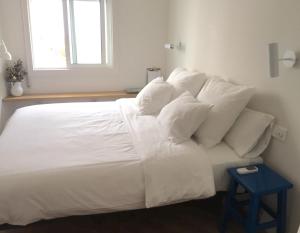 uma cama branca com lençóis e almofadas brancos em Lar Atlántica em Vigo