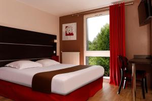 a bedroom with a bed and a window and a table at Hôtel Restaurant Le Colibri in Douvrin