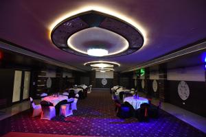 una sala da pranzo con tavoli, sedie e lampadario a braccio di Hotel Grand Rajputana a Raipur