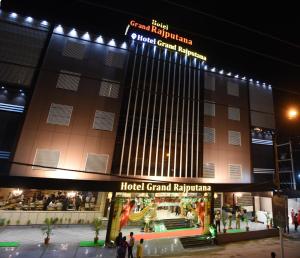 a hotel with people standing outside of it at night at Hotel Grand Rajputana in Raipur