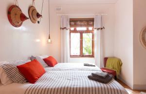 um quarto com uma cama com almofadas laranja e uma janela em Number5 Guesthouse em Cidade do Cabo