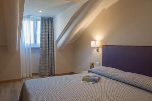 Un dormitorio con una cama con un libro. en Hotel Torino Porta Susa en Turín
