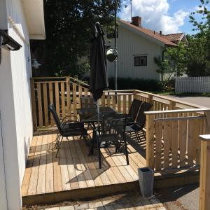 eine Holzterrasse mit einem Tisch, Stühlen und einem Sonnenschirm in der Unterkunft Blå Flagg in Köpingsvik