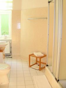 ein Bad mit einer Dusche, einem WC und einem Tisch in der Unterkunft Pension Brinn in Berlin