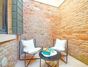 ヴェネツィアにあるDolceVita Apartments N 181のレンガの壁のパティオ(椅子2脚、テーブル1台付)