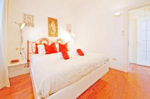 1 dormitorio con cama blanca y almohadas rojas en DolceVita Apartments N 241 en Venecia