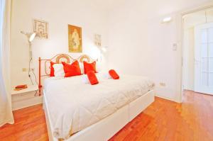 Un dormitorio con una cama blanca con almohadas rojas. en DolceVita Apartments N 241, en Venecia