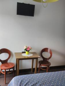 a table with three chairs and a table with flowers on it at Le Nouveau Monde in Breuillet