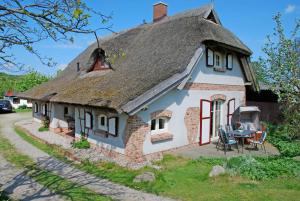 a small white house with a thatched roof at Ferienhaus unterm Reetdach in Ostseebad Sellin