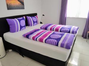 a bed with purple and purple pillows on it at Ferienwohnung im Atelierhaus in Meersburg