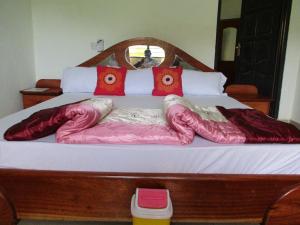a bed with red pillows and pink comforters on it at Paradise Ocean Resort in Cape Coast