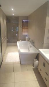 a white bathroom with a tub and a shower at Pearl of OysterBay in Westbrook