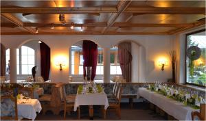 a dining room with tables and chairs and windows at Hotel Alpina nature-wellness in Wenns