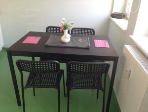 a table with four chairs and a vase with flowers on it at Wiesbaden Apartment in Wiesbaden +4 photos