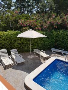 una sombrilla y sillas junto a la piscina en Casa Lorca, en Roses