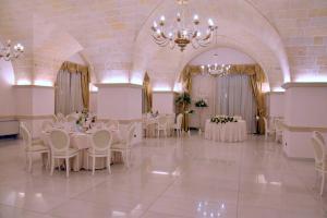 a banquet hall with white tables and chairs and a chandelier at Tenuta Caradonna in Lequile +78 photos