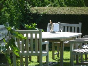 een witte tafel met twee stoelen en een wijnglas erop bij Manoir de Turqueville les Quatre Etoiles in Turqueville