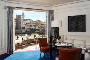 a living room with a table and a large window at Hotel Lungarno - Lungarno Collection in Florence