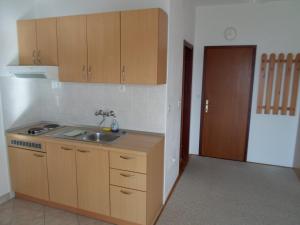 a kitchen with a sink and wooden cabinets and a door at Apartments Branko in Nin