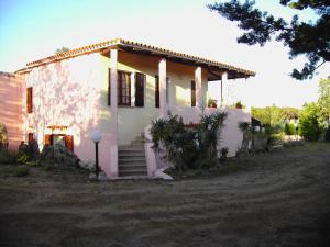 a small white house with a porch and stairs at La Cuppulata in Budoni