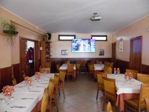 una sala da pranzo con tavoli, sedie e TV di Hotel Coste Del Lago a Limosano