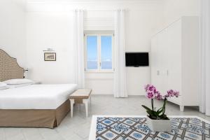 a white bedroom with a large bed and a tv at Hotel Villa Garden in Sant'Agnello