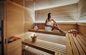 a woman is sitting in a sauna at Hôtel Juana in Juan-les-Pins