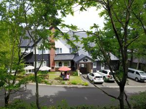 uma casa com carros estacionados ao lado da rua em White Rose Inn em Hachimantai