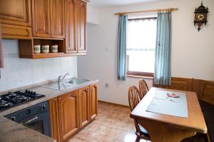 a kitchen with wooden cabinets and a table and a sink at Apartment pri Damijanu in Ponikve