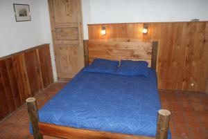 a bedroom with a blue bed with wooden walls at Le Berger Gourmand in Saint-Véran