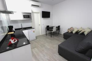 a living room with a black couch and a kitchen at Alma Suites in Madrid