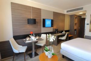a hotel room with a bed and a dining room at iH Hotels Milano Lorenteggio in Milan
