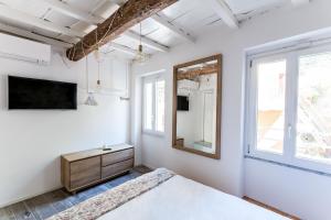 a white bedroom with a bed and a mirror at La Vista di Marina by The First in Riomaggiore