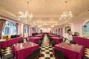 a banquet hall with pink tables and chairs and chandeliers at Jinhue Hotel in Luye
