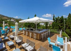 eine Terrasse mit Stühlen und einem Tisch mit einem Sonnenschirm in der Unterkunft Asteria Hotel in Tolo