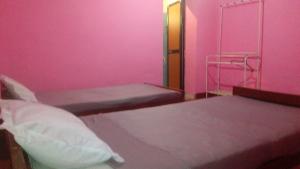 a pink room with two beds and a towel rack at Sembuwatta Reach Homestay in Elkaduwa