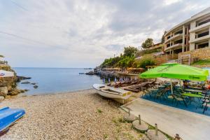 a beach with a green umbrella and a boat on the shore at Teuta Apartments in Ulcinj