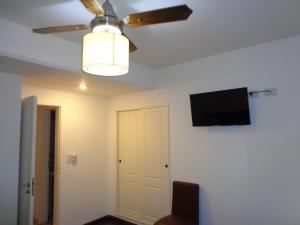 a room with a ceiling fan and a tv on the wall at Al Mar Departamentos in Puerto Madryn