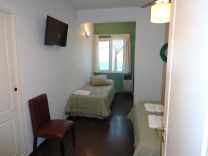 a room with two beds and a chair and a window at Al Mar Departamentos in Puerto Madryn