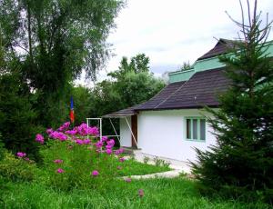 a white house with pink flowers in the yard at Fisherman's Cottage in Cacica