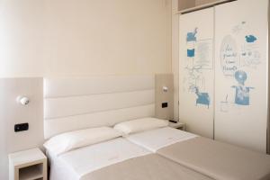 a small white bedroom with a bed and a mirror at Hotel Nettuno in Pesaro