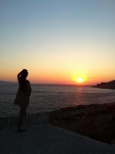 Arki Island-Katsavidis في Arkoi: امرأة تقف على الحائط وتطل على غروب الشمس
