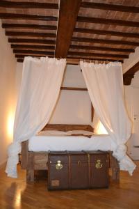 シエナにあるDimora storica - Palazzo Barabesiのベッド(カーテン付)とスーツケースが備わります。