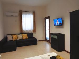 un soggiorno con divano nero e TV di Casa Vacanze Rosalia - affitto breve a Santo Stefano di Camastra