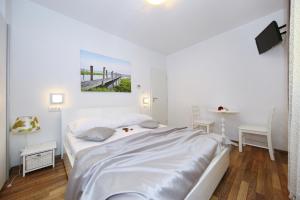 a white bedroom with a bed and a table at Apartments Maruna Self check-in in Zadar