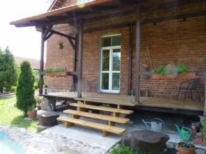 Sloneczna Weranda في فودميني: منزل من الطوب مع شرفة خشبية والدرج