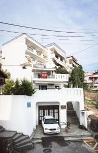 une voiture blanche garée devant un bâtiment dans l'établissement Aria's House Studios & Apartments, à Neos Marmaras