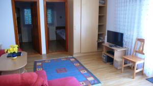 a living room with a couch and a table and a tv at Nyáridő Apartman in Alsóörs