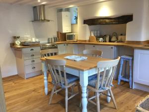 a kitchen with a wooden table and chairs at Pilchards Cottage in Noss Mayo +49 photos