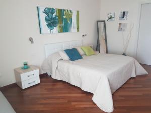 1 dormitorio con cama blanca y suelo de madera en Residenza Piazza Moro, en Bari